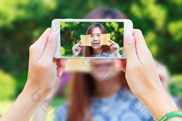 <strong>手持</strong>智能手机的男子在度假村为亚洲少女<strong>拍照</strong>并享用早餐。