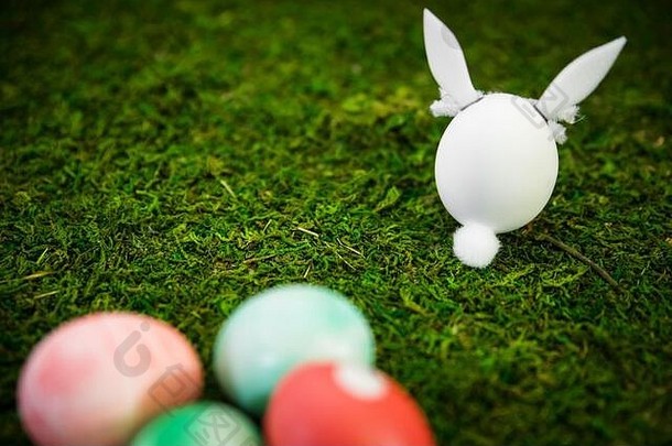 背景：绿色苔藓上的复活节兔子和彩色染色复活节彩蛋