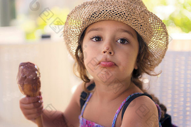 戴着草帽，穿着太阳裙的小女孩享受着<strong>夏日</strong>的酷热，她吃着一个令人耳目一新的甜筒巧克力<strong>冰淇淋</strong>，<strong>冰淇淋</strong>融化在她的手上，她有着最棒的身材