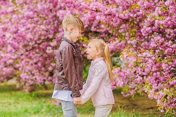 爱在空气中。温柔的爱情。小女孩和男孩。在公园里的浪漫<strong>约会</strong>。<strong>春</strong>天是坠入爱河的时候。恋爱中的孩子粉色樱花。一对可爱的孩子漫步樱花花园。