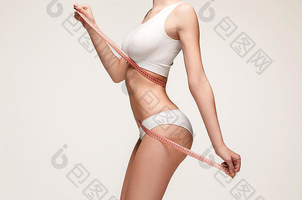 女孩正在测量她的身体，白色背景。