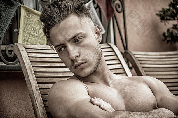 赤膊上阵年轻的男人。干燥热太阳肌肉发达的男人。日光浴海滩休息室椅子