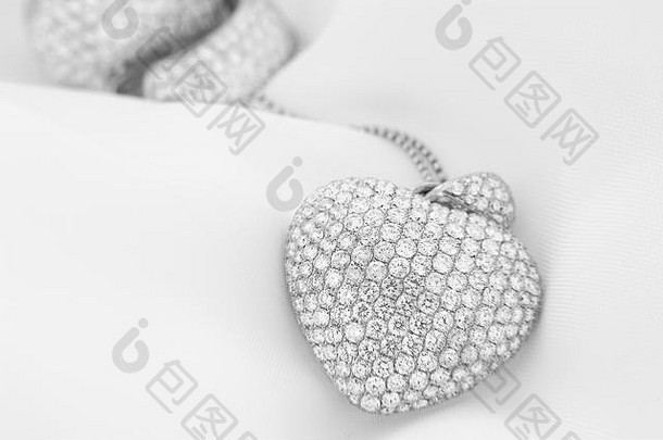 白金耳环和心形项链，白色钻石镶嵌在柔和模糊的背景上