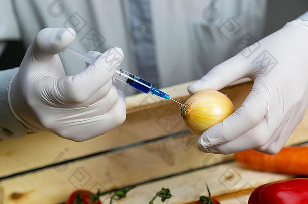 一名男子用注射器向洋葱、转基因肥料和化学品中注入化学物质，以延长蔬菜的保质期。