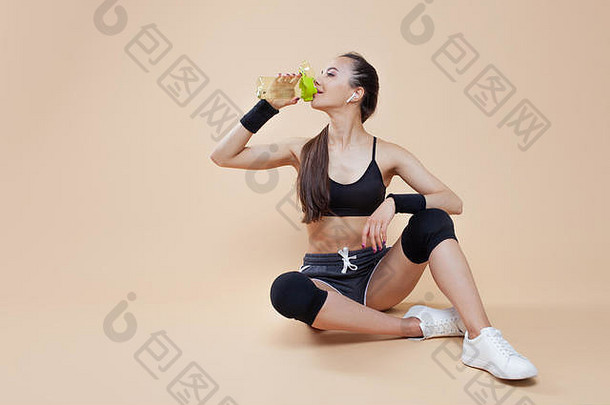 可爱的运动浅黑肤色的女人女孩紧身体育统一的坐在休息锻炼黑色的膝盖骨瓶体育营养