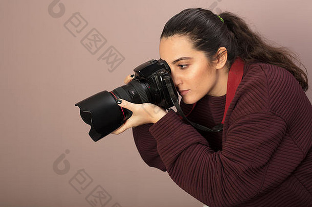 年轻的女摄影师用专业的单反相机拍摄照片，镜头向前弯曲，从侧面聚焦拍摄对象