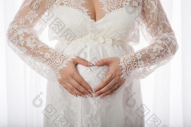 女人的手举行形状心怀孕了肚子穿花边孕妇礼服