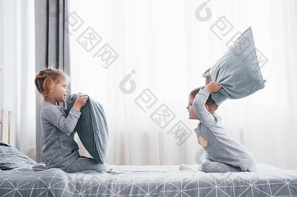 男孩女孩上演了枕头战斗床上卧室淘气的孩子们击败枕头种类游戏