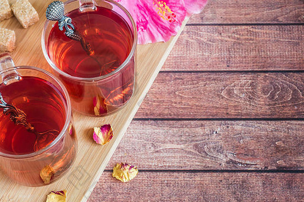 玻璃杯红色的茶粉红色的芙蓉花黑暗木背景