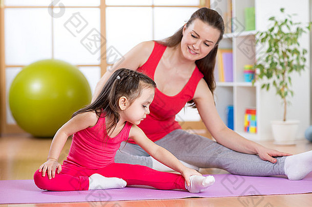 母女俩在家里的垫子上做健身操