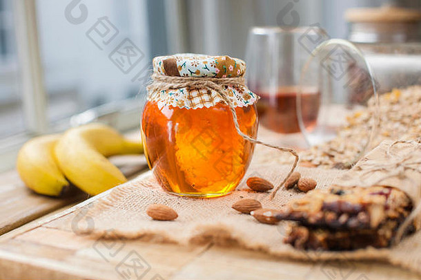 茶，坚果，蜂蜜，放在罐子里，香蕉放在靠近眼睛的木桌上。健康早餐。复古照片。
