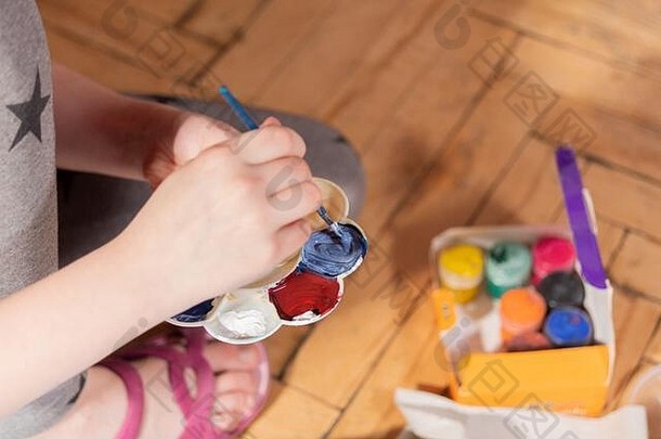 孩子搅拌颜料。一套油漆和刷子。婴儿身体的一部分。