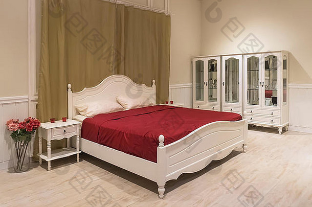 白色木床，深红色毯子和白色枕头。