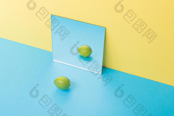 在镜子附近的黄色背景上隔离的蓝色桌子上的石灰图片