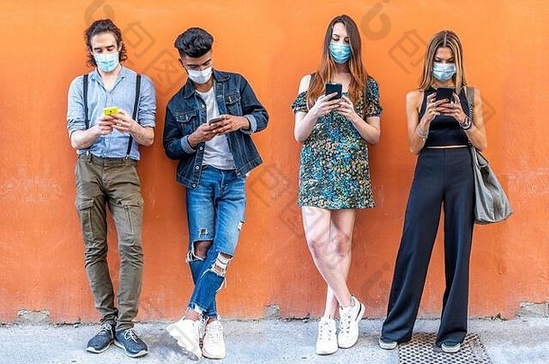 一群戴着口罩的多种族朋友使用智能手机在社交网络上共享内容