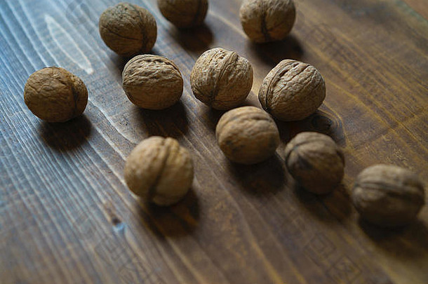 在古老的棕色木质背景上，以<strong>原汁原味</strong>的有机胡桃壳为质朴风格。从乡下收割坚果。健康的饮食成分。闭合。