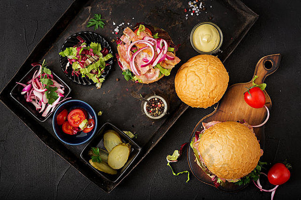 大三明治-汉堡汉堡配牛肉、西红柿、腌黄瓜和炸培根。平铺。俯视图