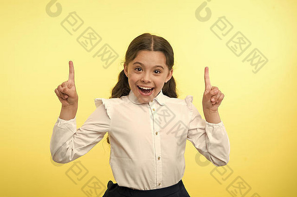 小天才有个主意。快乐女孩在黄色背景上竖起手指。回到学校。这个小孩带着灵感微笑。好主意。只是灵感。无忧无虑的美丽。