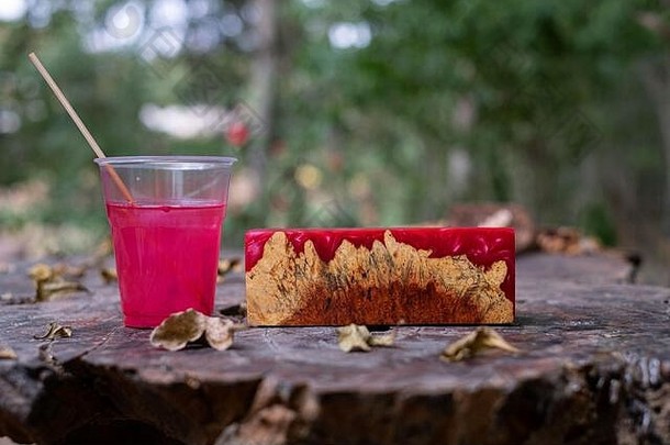 在旧桌子艺术背景上铸造红色环氧树脂burl木材立方体，自然Afzelia木制
