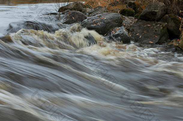 秋天，河水湍急，岸边有带落叶的巨石