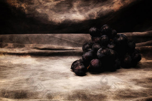 一束黑色无籽葡萄，背景为灰色斑驳，装裱、构图和拍照<strong>都与</strong>老式静物画相似。