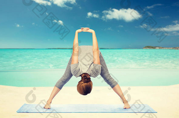 在海滩上做瑜伽前弯的女人