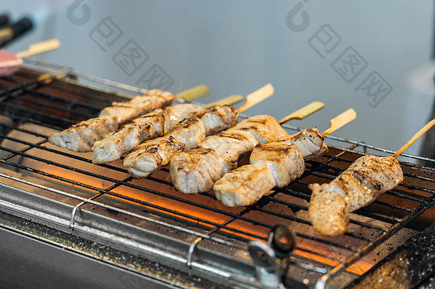烤架上有新鲜的金鱼条。生金鱼肉是在鱼市上烤的串肉。