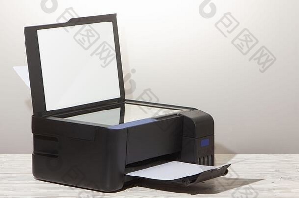 白色木桌上的黑色复印机，特写。