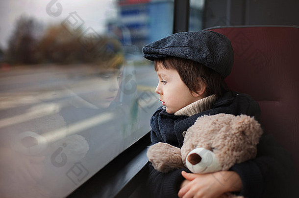 甜蜜的孩子学前教育男孩骑公共汽车白天持有泰迪熊