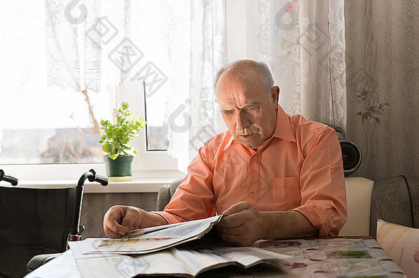 特写这位秃头老人坐在靠近窗户的起居室里<strong>阅读小报</strong>上的最新消息。