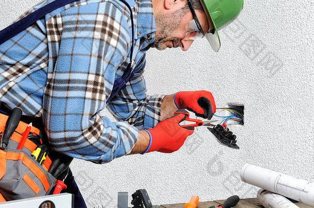 手戴手套和绝缘工具的电工在住宅电气装置中遵守安全规定。