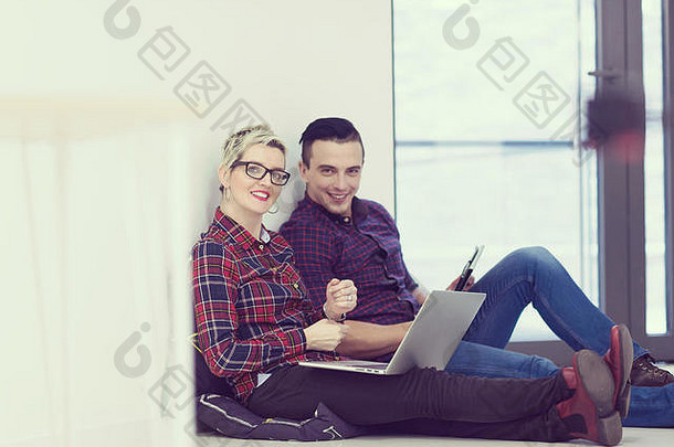 初创企业和新的移动技术概念，年轻夫妇在现代明亮的办公室室内，在新cre上使用笔记本电脑和平板电脑