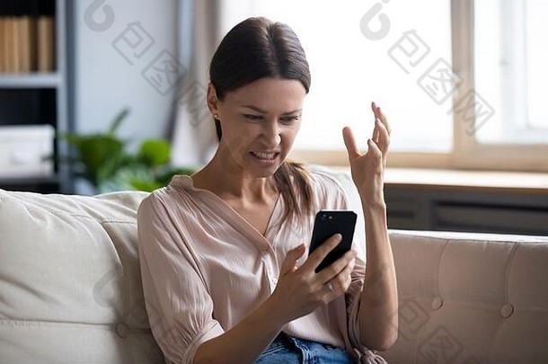 恼怒的年轻女子看着手机屏幕。