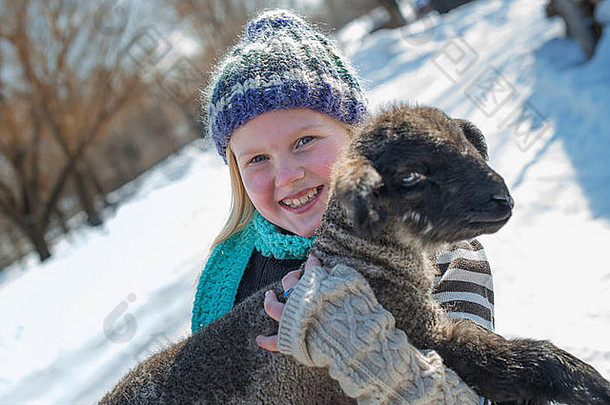 冬天的景色雪地上一个小女孩抱着一只小羊羔