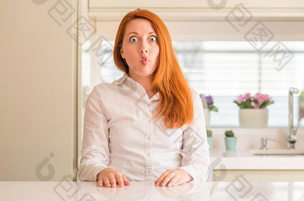 红发女人在厨房用嘴唇<strong>做鱼</strong>脸，疯狂而滑稽的姿势。滑稽的表情。