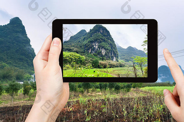 旅游理念-游客在智能手机上拍摄中国阳朔县春季喀斯特山脉附近的花园-