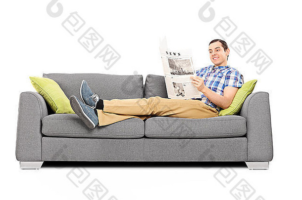 年轻的快乐男人。阅读新闻沙发孤立的白色背景
