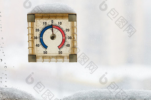 在温暖的冬日，被雪覆盖的家中窗户温度计