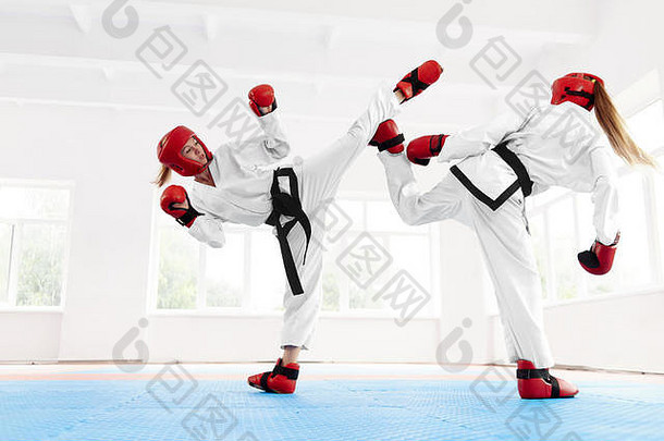 年轻的女拳击手戴着特制的红色防护手套和头盔，配上打斗鞋，拳击时使用空手道技术拳打脚踢。两个女孩在特别班一起训练空手道。