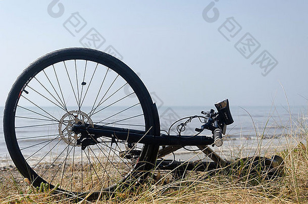 在一个阳光明媚的三月天，一辆黑色自行车停在沙丘上，守卫着坎布里亚海滩