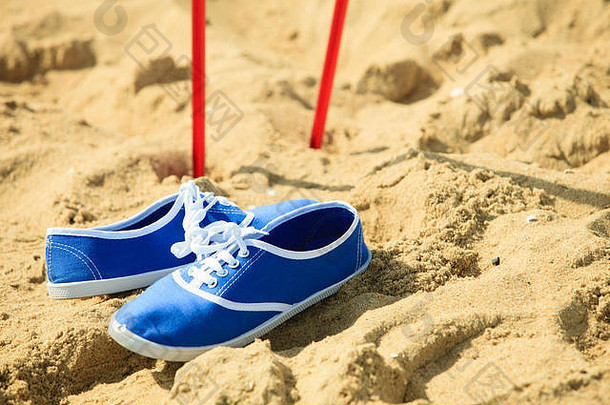 北欧步行设备。沙滩上的树枝和蓝色鞋子。