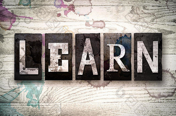 单词“学习”是用老式脏金属活版印刷字体写在有墨水和油漆污渍的白色木质背景上的。
