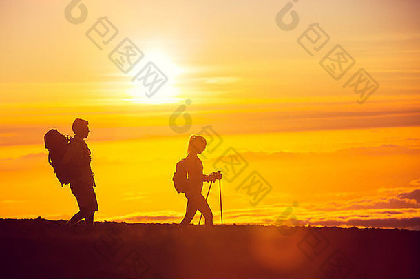 日落时分，两个背着背包的徒步旅行者的剪影。徒步旅行，从山顶欣赏日落美景
