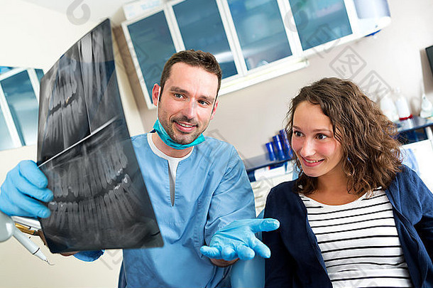 一位年轻迷人的牙医向患者展示x光片的画面