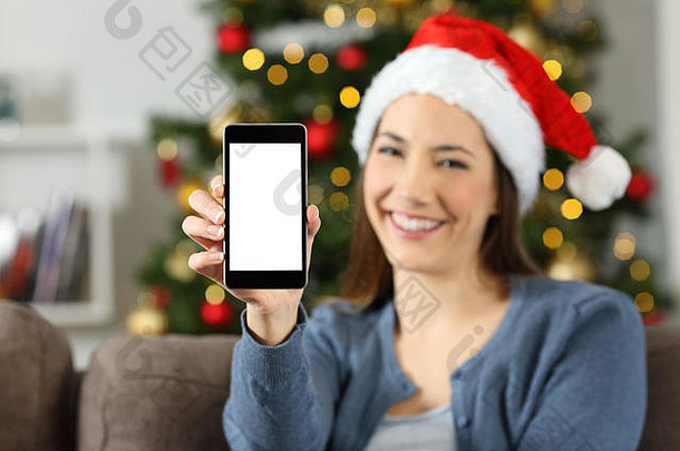 前面视图肖像快乐女人显示聪明的电话屏幕圣诞节坐着沙发上生活房间首页