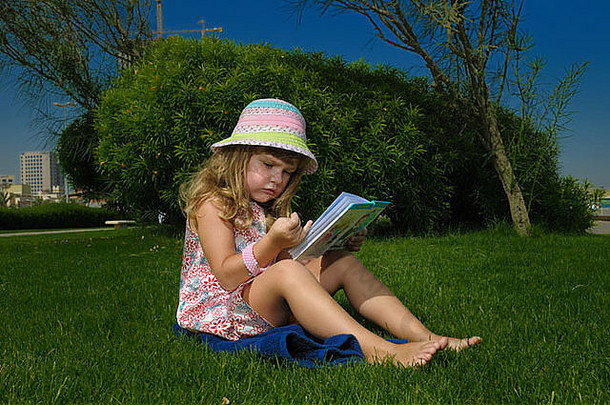 那个小女孩正坐在草地上看书。