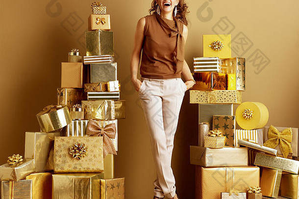 完整的长度肖像微笑时尚的购物者女人黄金米色裤子棕色（的）上衣桩金礼物前面平原墙空心