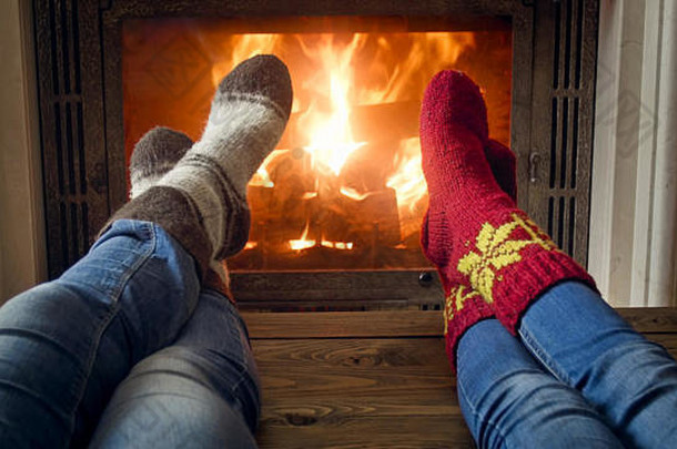 一对浪漫夫妇的特写镜头，牛仔裤和羊毛袜在房子的<strong>熊熊大火</strong>中取暖