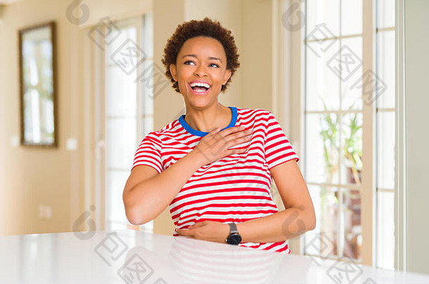 年轻漂亮的非洲裔美国妇女在家里笑得很大声，因为有趣的疯狂笑话。高兴的表情。