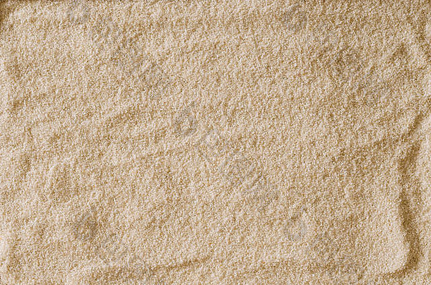 粗糙不平的空砂表面，用作背景或纹理。浅棕色和赭色的沙粒。宏观照片特写从上面。
